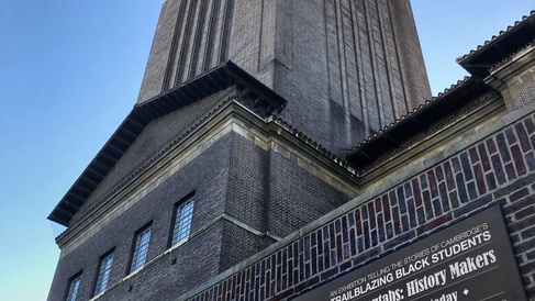 Exterior view of Cambridge University Library with a freestanding exhibition display board positioned in front of the building