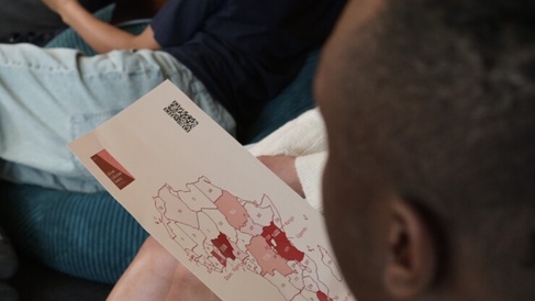 A person seated in a group holds a printed map of Africa shaded in various red tones