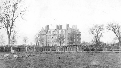 Historic photograph of Newnham College buildings across open grounds.