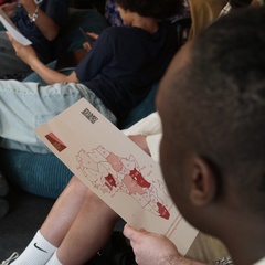 A person seated in a group holds a printed map of Africa shaded in various red tones