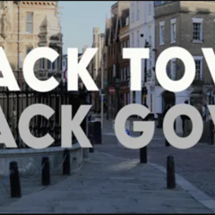 Large white text reading “BLACK TOWN BLACK GOWN” over a street scene in Cambridge, with historic buildings and railings visible in the background.