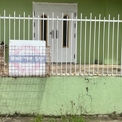 A house in Trinidad and Tobago with a “Mind the Gap” sign on its fence, photographed in a residential street