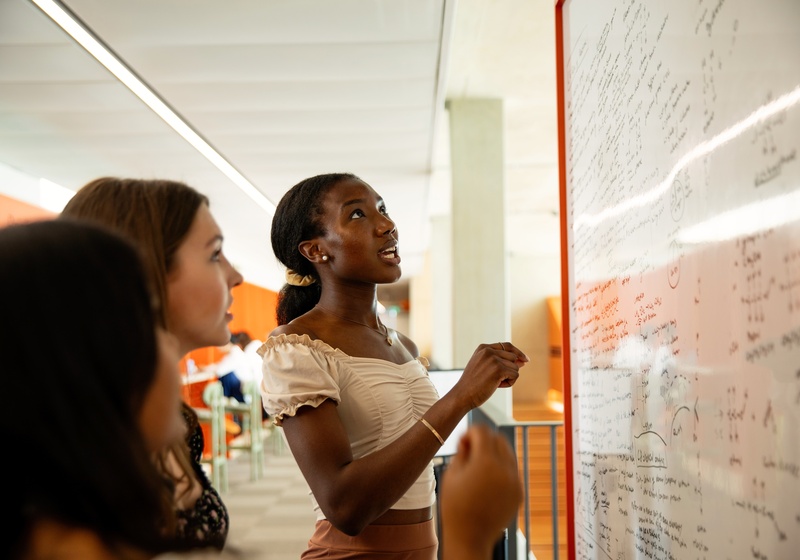 Students looking at whiteboard with handwritten notes and ideas