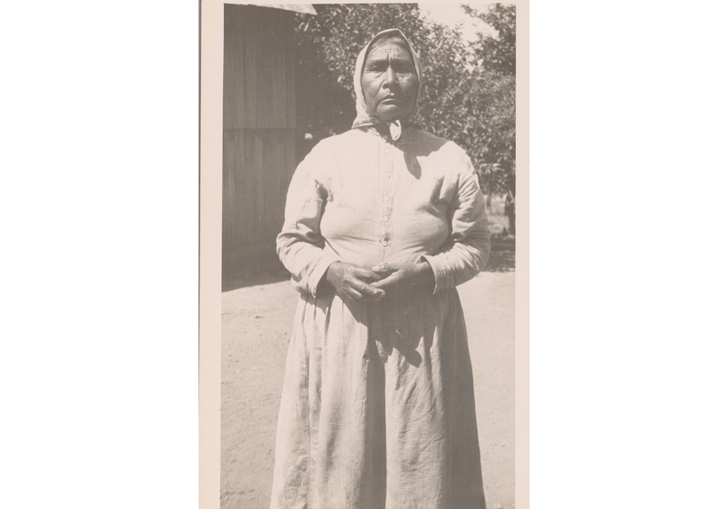Portrait of Lucy Young (T’tc~tsa) standing outdoors, wearing a long dress and headscarf, photographed in California, 1922